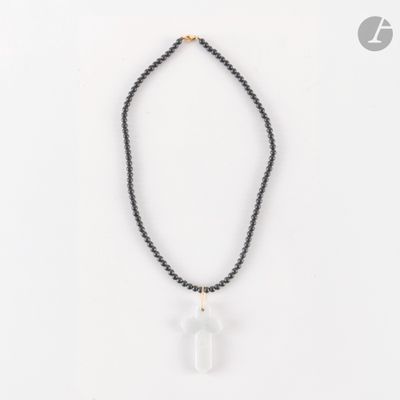un collier de perles noires orné d'un pendule en quartz transparent
