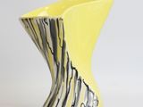 a yellow vase with a black and white design on it