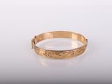 gros plan d'un bracelet en or sur une surface blanche