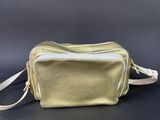 a gold purse with a white strap on a black background