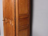 a tall wooden cabinet with two doors on top of it