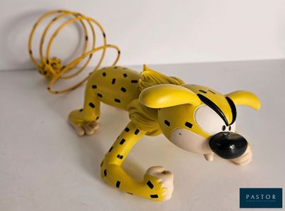 un jouet représentant un guépard allongé sur une surface blanche