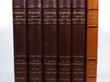 six brown books are lined up in a row on a white surface