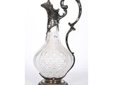 an antique silver and glass pitcher on a stand on a white background