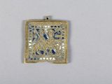 un gros plan d'un pendentif doré et bleu sur une surface blanche