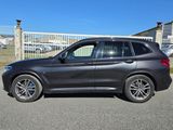 La BMW X3 est garée devant une clôture