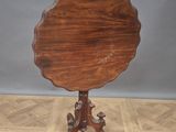 an antique mahogany tilt top table on a wooden stand on a parquet floor