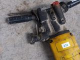 a yellow and black drill on the ground next to a yellow and black hammer