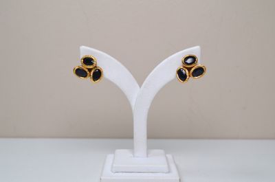 a close up of a pair of black and gold earrings on a white stand