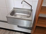 un lavabo dans un coin de la salle de bains, avec une étagère en bois