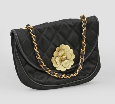un sac à main noir matelassé orné d'une fleur dorée