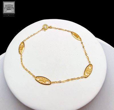 bracelet plaqué or sur une assiette blanche avec un fond noir