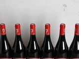 six bottles of red wine lined up in a row on a table