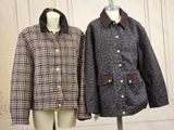 pair of coats on mannequins in front of wallpapered wall
