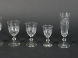 six glass goblets are lined up in a row on a black surface