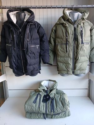deux vestes et un sac posés sur une étagère dans une pièce