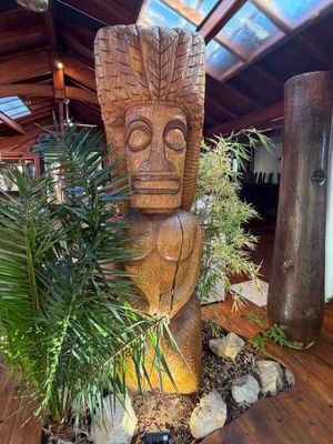 a wooden statue in the middle of a room with a potted plant in it