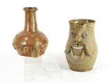 two vases with faces on them sitting on a stand