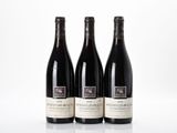 three bottles of red wine are lined up on a white surface