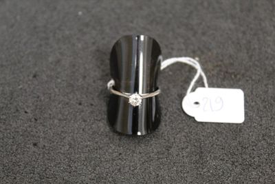 une bague sertie d'un diamant, posée à côté d'une étiquette de prix