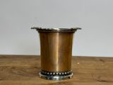 silver plated cup on wooden table with white wall in background