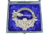 an antique silver broochle in a velvet case with a blue velvet lining