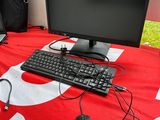 a desk with a computer, keyboard, mouse, and bag on it