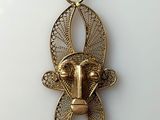 a close up of a gold necklace with an animal on it