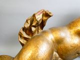 une statue en or représentant une femme allongée sur une surface blanche