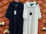 two polo shirts hanging on a wall next to a vase of flowers