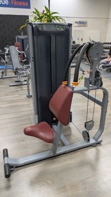 a gym room with machines and a plant in the middle of the room