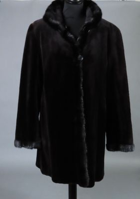 Le manteau est noir et est orné d'un col en fourrure.