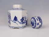 two blue and white vases and a small container on a table