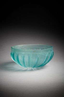 un saladier en verre bleu-vert posé sur une surface blanche