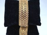 une photo d'un bracelet en or posé sur un coussin en velours noir
