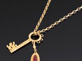 un collier en or orné d'une pierre rouge et d'une clé