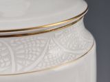 a white vase with gold trim and a lid