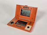 une petite console de jeux orange posée sur une surface blanche