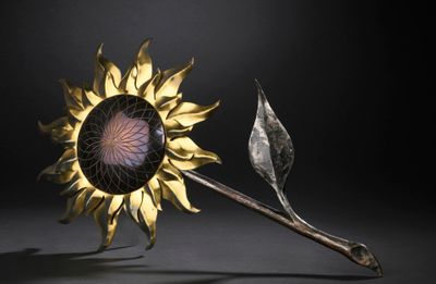 an image of a metal sunflower with a stem and a leaf