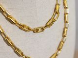a close up of a gold chain necklace on a mannequin