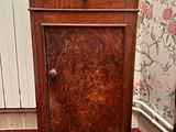 un petit meuble en bois avec un plateau en marbre, posé sur un tapis rouge