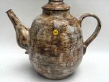 une théière marron sur laquelle est collée une étiquette jaune