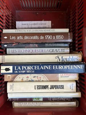 de nombreux livres dans un panier rouge posé sur l'étagère