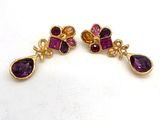 une paire de boucles d'oreilles ornées de pierres violettes sur un fond blanc
