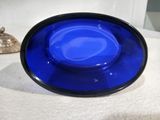 un saladier en verre bleu posé sur une nappe blanche