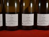 four bottles of wine are lined up on a red cloth