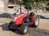 un tracteur rouge garé sur la terre battue