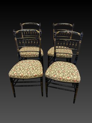 quatre chaises noires dont les assises sont recouvertes d'un tissu à motifs floraux sur fond noir