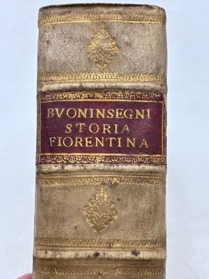Une personne tient dans sa main un vieux livre sur lequel sont inscrits des mots