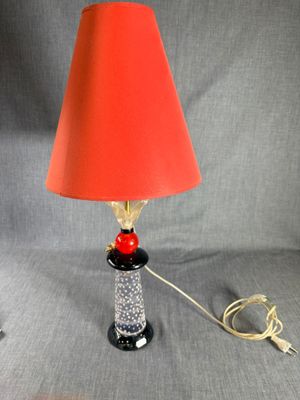 une image représentant une lampe avec un abat-jour rouge et un pied noir